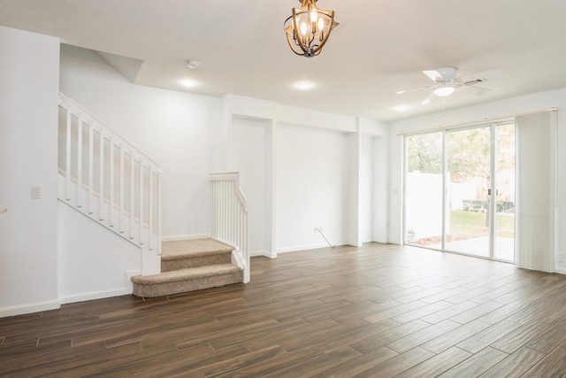 spare room with baseboards, dark wood-type flooring, stairs, and ceiling fan with notable chandelier