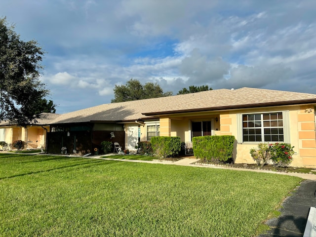 single story home with an attached garage, a shingled roof, a front lawn, and stucco siding