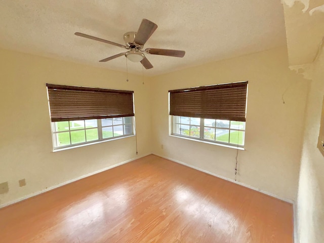 empty room featuring ceiling fan, a textured ceiling, light hardwood / wood-style flooring, and a wealth of natural light