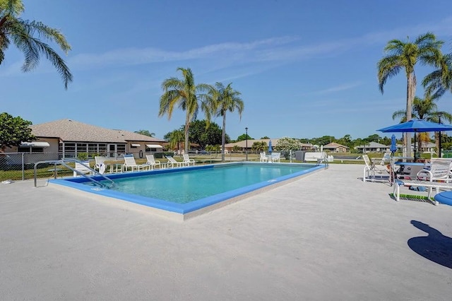 pool with a patio area and fence