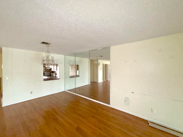 spare room featuring hardwood / wood-style flooring, a chandelier, and a textured ceiling