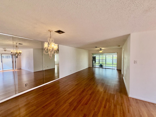 unfurnished room featuring a textured ceiling, visible vents, wood finished floors, and ceiling fan with notable chandelier