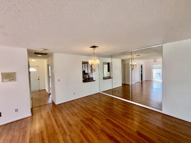 spare room with a textured ceiling, visible vents, and wood finished floors