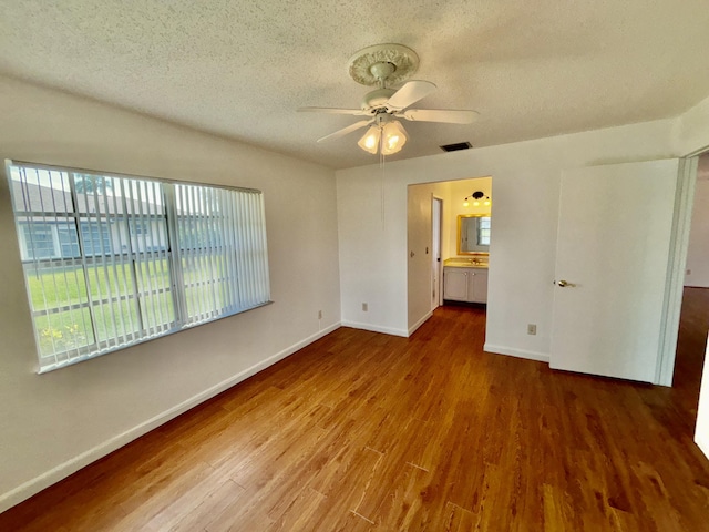 unfurnished bedroom featuring visible vents, a textured ceiling, baseboards, and wood finished floors