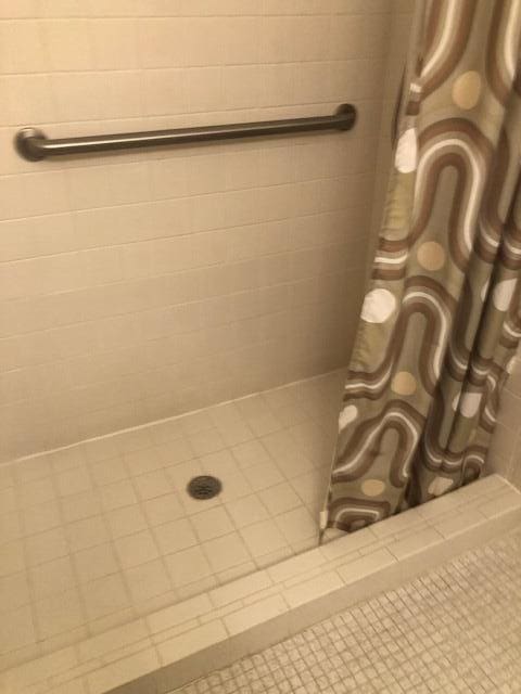 bathroom with tiled shower and tile patterned floors