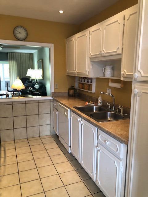 kitchen featuring white cabinetry, sink, white dishwasher, and light tile patterned floors