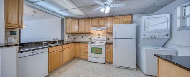 kitchen featuring a paneled ceiling, white appliances, sink, stacked washer and clothes dryer, and light tile patterned floors