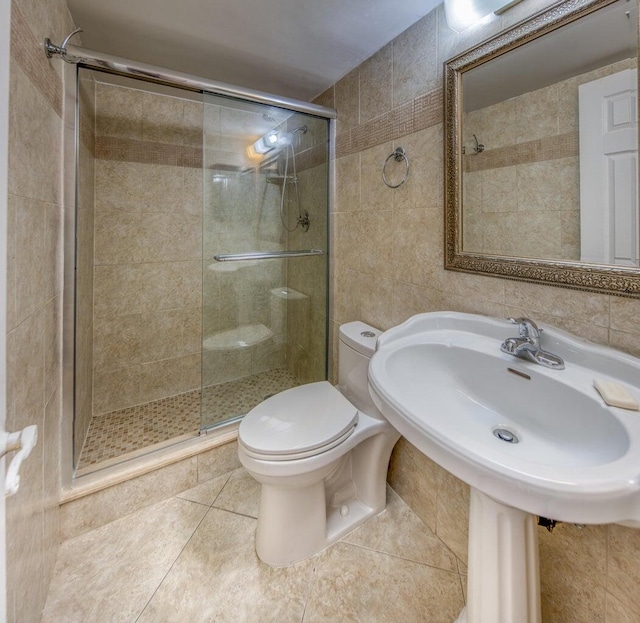 bathroom with tile walls, a shower with door, and toilet