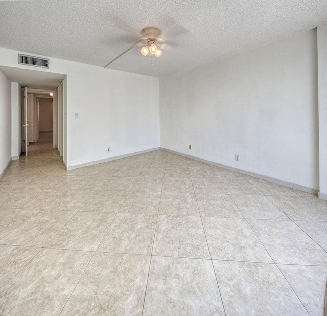 empty room with ceiling fan, light tile patterned floors, and a textured ceiling