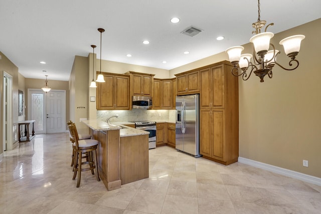 kitchen featuring light stone counters, pendant lighting, kitchen peninsula, appliances with stainless steel finishes, and a breakfast bar