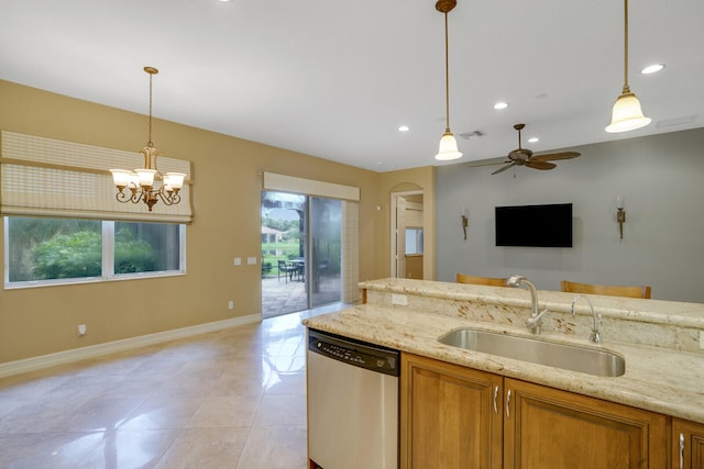 kitchen with light stone counters, sink, stainless steel dishwasher, decorative light fixtures, and ceiling fan with notable chandelier