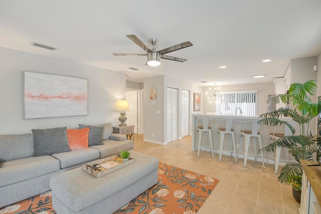 living room with ceiling fan with notable chandelier and light tile patterned floors