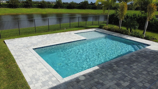 view of swimming pool featuring a patio area, a water view, and a lawn