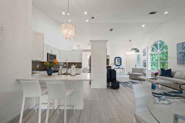 4561 Carlton Golf Dr, Lake Worth, FL 33449 - kitchen with open floor plan, a chandelier, light wood finished floors, stainless steel microwave, and a peninsula