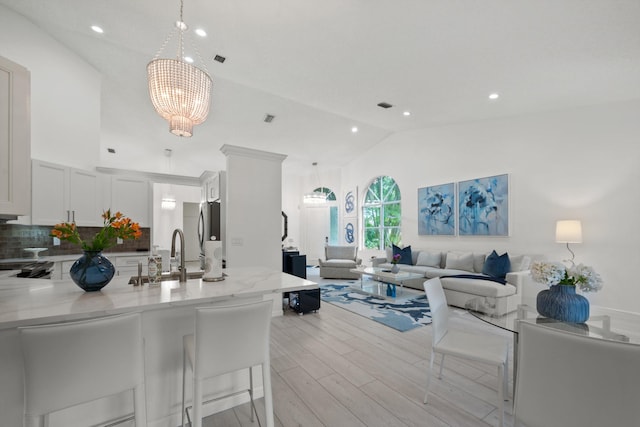 4561 Carlton Golf Dr, Lake Worth, FL 33449 - kitchen with light wood finished floors, light stone counters, a peninsula, open floor plan, and a notable chandelier