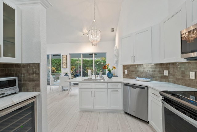 4561 Carlton Golf Dr, Lake Worth, FL 33449 - kitchen with white cabinets, backsplash, a notable chandelier, beverage cooler, and appliances with stainless steel finishes