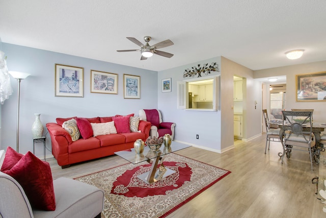 living room with light hardwood / wood-style flooring, a textured ceiling, and ceiling fan