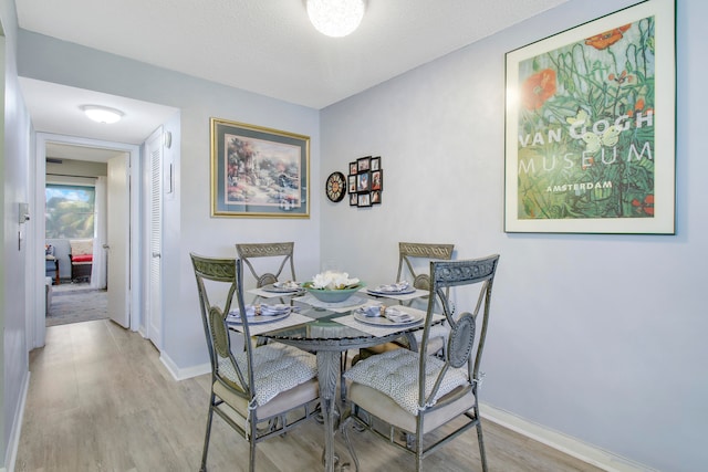 dining area with a textured ceiling and light wood-type flooring