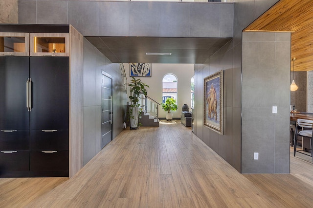 hall featuring light wood-type flooring and a high ceiling