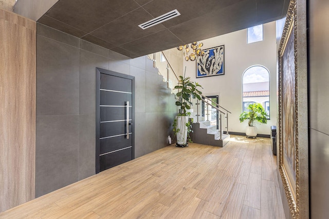 foyer with hardwood / wood-style floors, a towering ceiling, and a notable chandelier