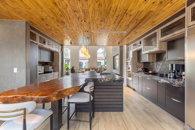 kitchen featuring decorative backsplash, light wood-type flooring, wood ceiling, sink, and decorative light fixtures