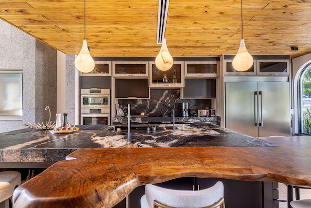 kitchen featuring pendant lighting, a breakfast bar, wood ceiling, and stainless steel appliances