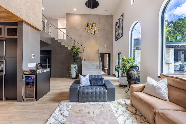 living room featuring indoor bar, a high ceiling, light wood-type flooring, and beverage cooler