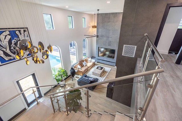 living room with a towering ceiling, ceiling fan with notable chandelier, and light hardwood / wood-style flooring