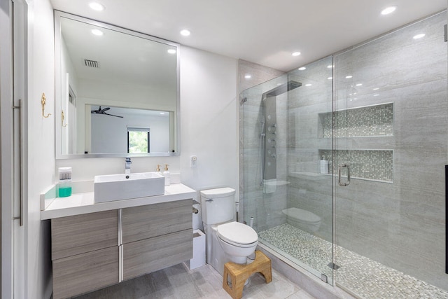 bathroom featuring ceiling fan, a shower with door, vanity, and toilet