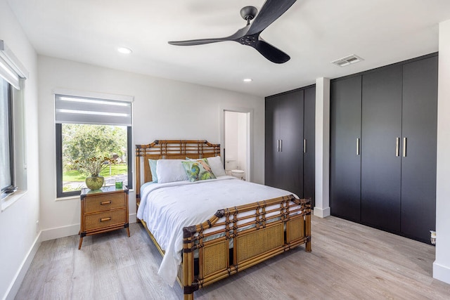 bedroom with two closets, light hardwood / wood-style floors, and ceiling fan