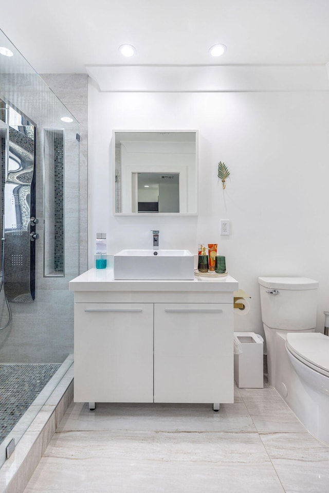 bathroom with tiled shower, vanity, and toilet