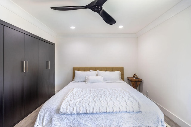 bedroom featuring a closet, light hardwood / wood-style flooring, ceiling fan, and ornamental molding