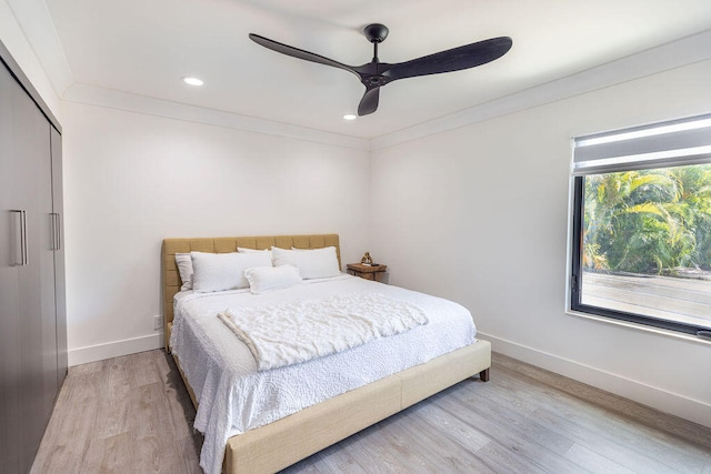 bedroom with ceiling fan, light hardwood / wood-style floors, crown molding, and a closet