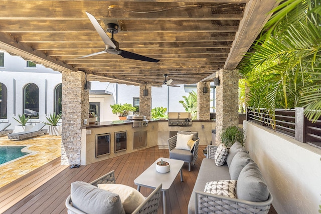 wooden terrace with ceiling fan, exterior kitchen, beverage cooler, an outdoor living space, and grilling area