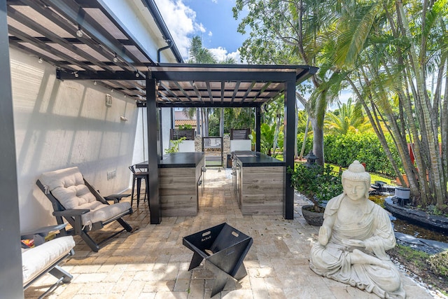 view of patio with area for grilling, a pergola, and an outdoor bar