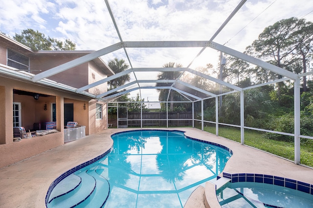 view of pool featuring a jacuzzi, glass enclosure, and a patio