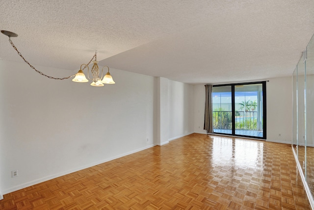 unfurnished room with light parquet floors, an inviting chandelier, and a textured ceiling