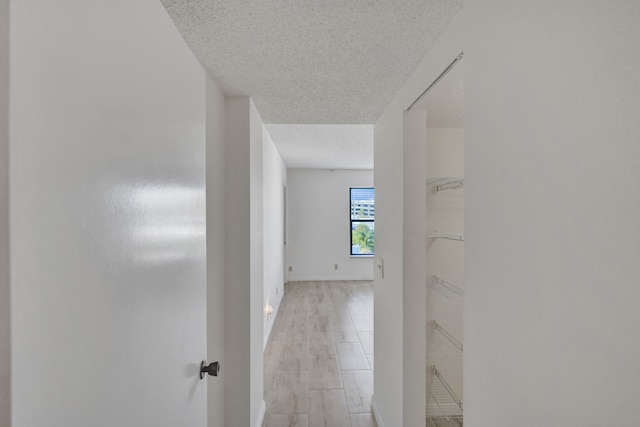 corridor featuring light hardwood / wood-style flooring and a textured ceiling