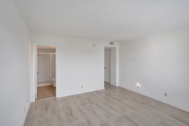 spare room with a textured ceiling and light hardwood / wood-style flooring