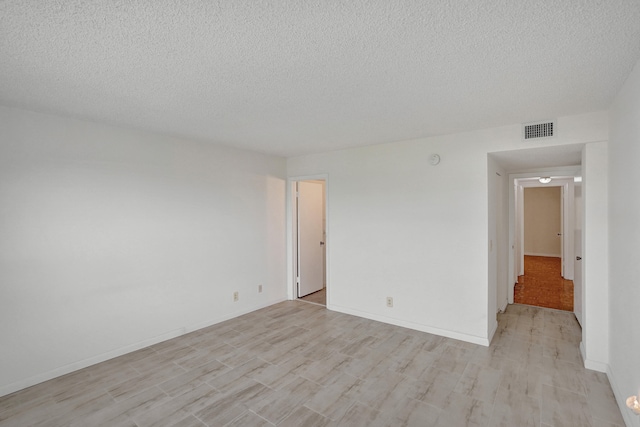 unfurnished room featuring light wood-type flooring and a textured ceiling