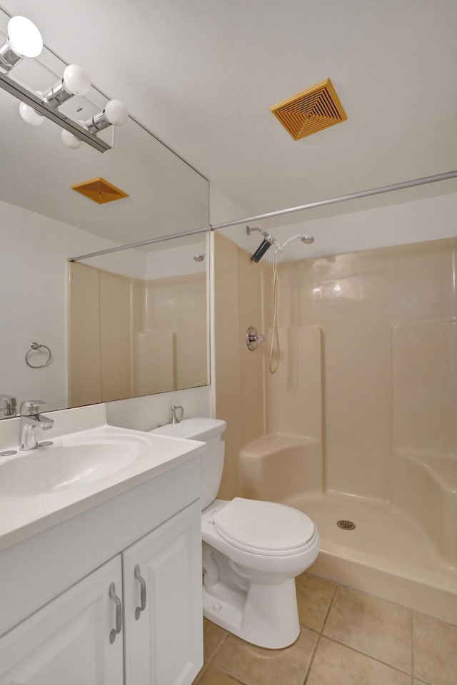 bathroom with toilet, vanity, tile patterned flooring, and walk in shower