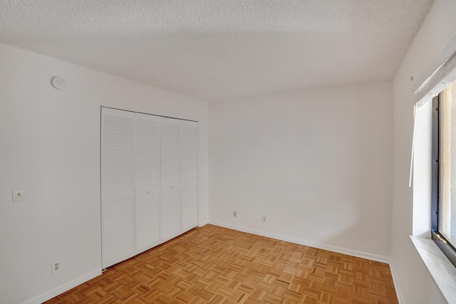 unfurnished bedroom with light parquet floors and a textured ceiling