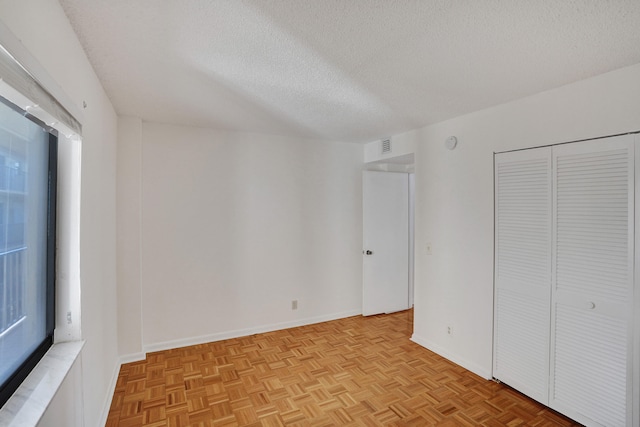 unfurnished bedroom featuring a textured ceiling and light parquet floors