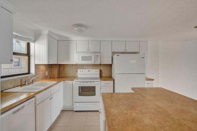 kitchen with light tile patterned flooring, sink, tasteful backsplash, white appliances, and white cabinetry