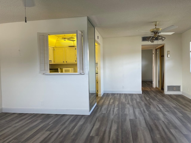 empty room featuring dark wood-type flooring, ceiling fan, and a textured ceiling