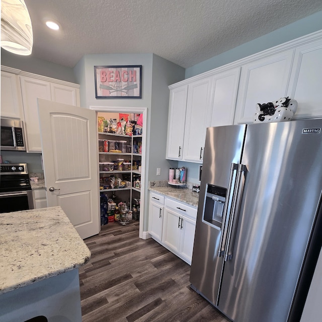 kitchen with light stone countertops, stainless steel appliances, dark hardwood / wood-style flooring, and white cabinetry