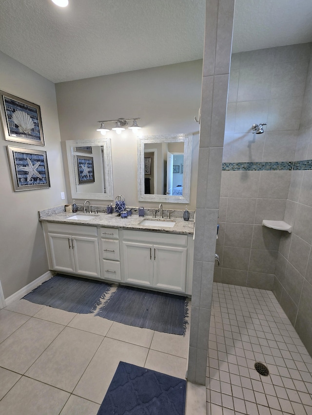 bathroom featuring tile patterned floors, a tile shower, vanity, and a textured ceiling