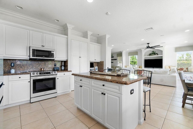 kitchen with stainless steel appliances, white cabinets, a center island, and ceiling fan