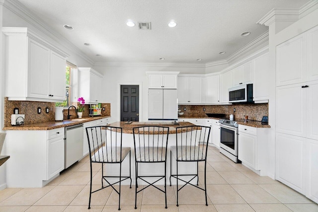 kitchen with ornamental molding, white cabinets, appliances with stainless steel finishes, and a kitchen island