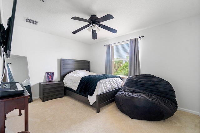 carpeted bedroom featuring ceiling fan and a textured ceiling